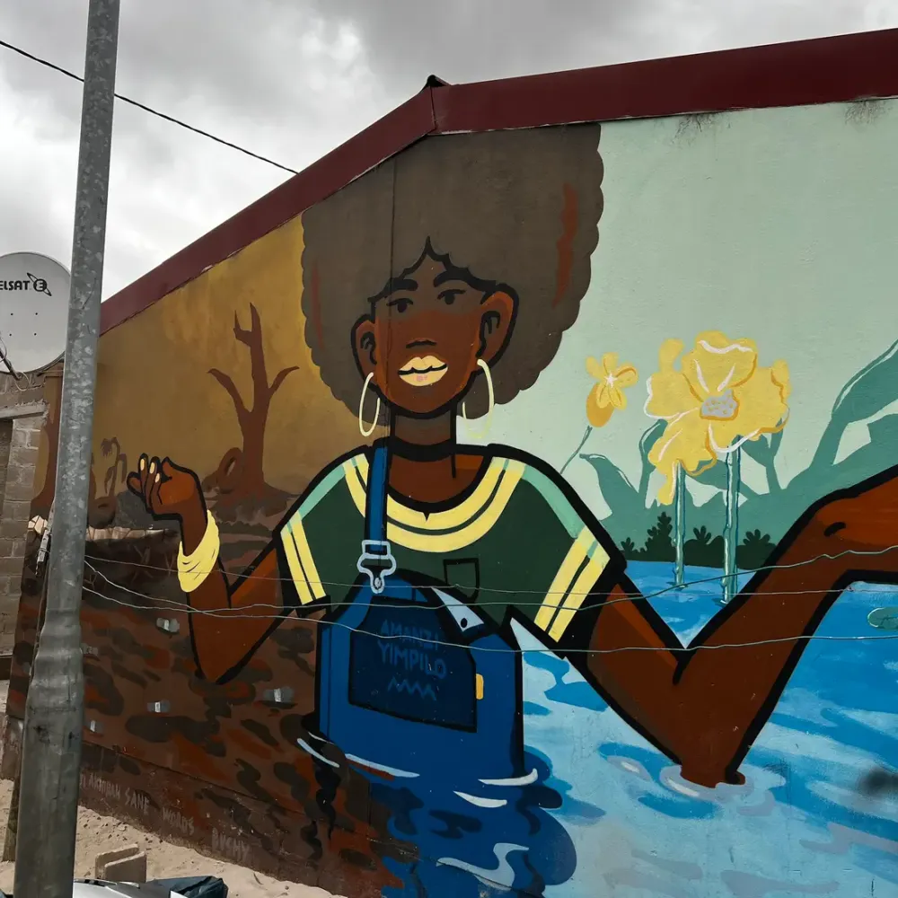 Mural of a woman standing in water on the side of a house