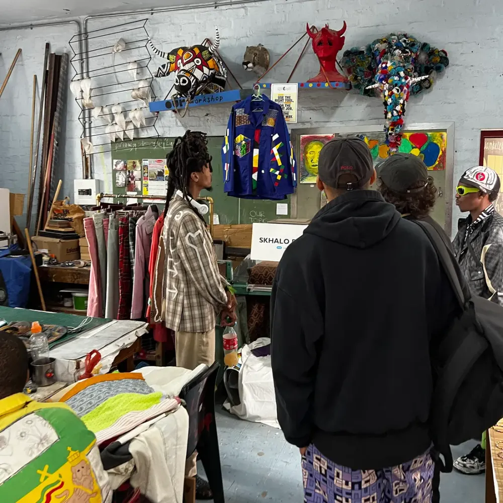 Guests in the clothing workshop, masks and garments on the wall