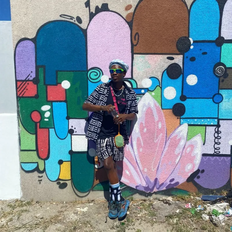Masande in a black and white outfit in front of a mural