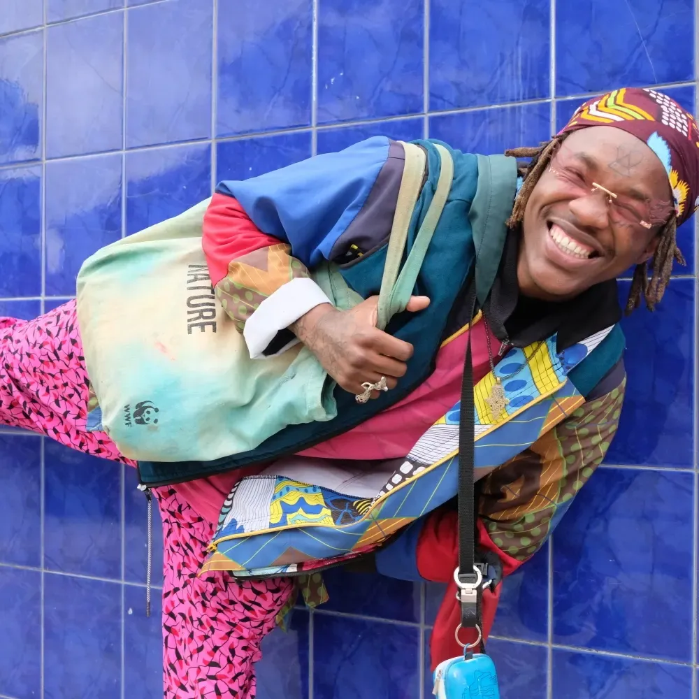 Masande laughing in front of a blue tiled wall
