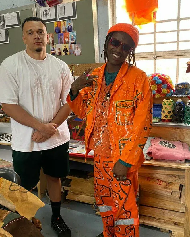Masande in an orange suit with a guest at a workshop