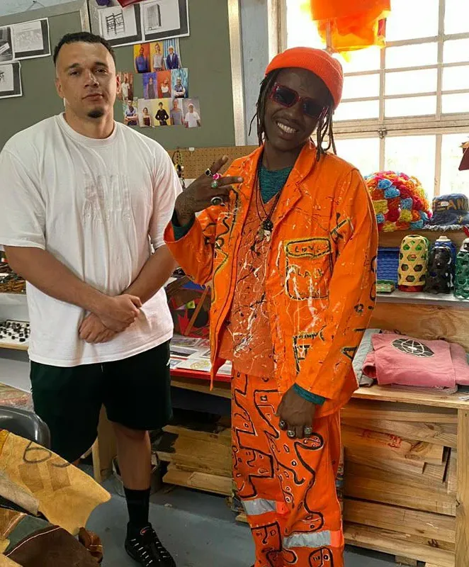 Masande in an orange suit with a guest at a workshop