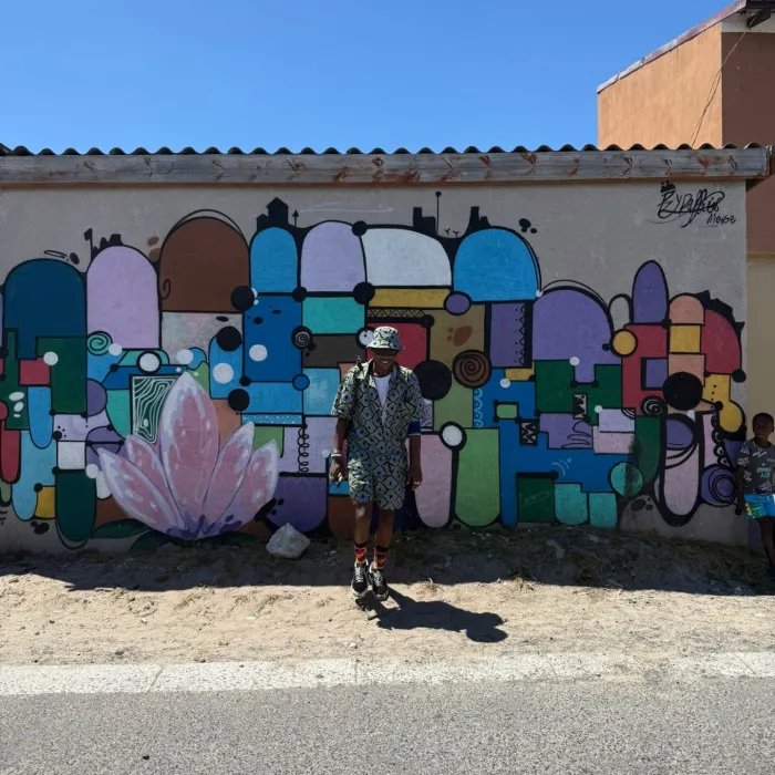 Masande standing in front of a street art mural in Langa